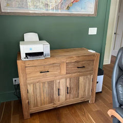 Wooden cabinet with a printer on top against a green wall.