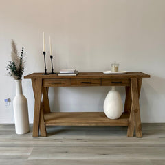Wooden console table with decorative items against a plain wall.