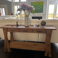 Wooden console table in a living room with a white sofa and decorative items.